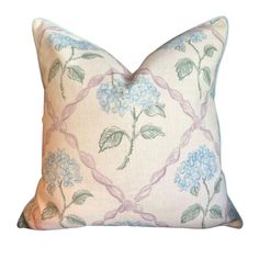 a white pillow with blue and pink flowers on the front, sitting against a white background