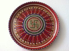 a decorative red plate with the letter e on it's center, decorated with beads and sequins