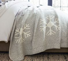 a bed with white snowflakes on it next to a window