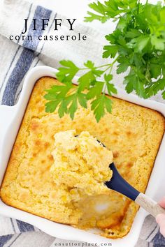 a person holding a spoon in a casserole dish with parsley on top