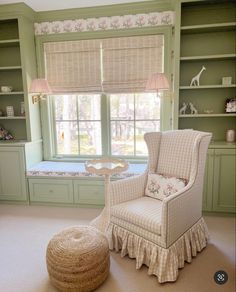 a chair and ottoman in front of a window with green walls, white carpet and built - in bookshelves