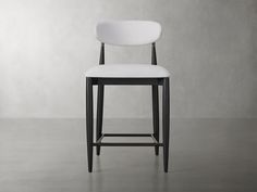 a white counter stool sitting on top of a cement floor next to a gray wall