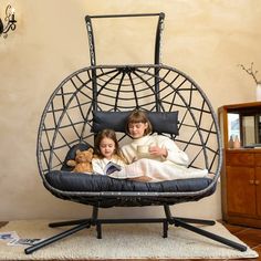 two children are sitting in a swing chair