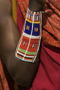 an african woman wearing a colorful beaded bracelet on her arm and headdress