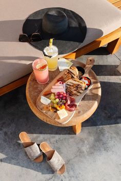 a table with food and drinks on it next to a hat, sunglasses and sandals