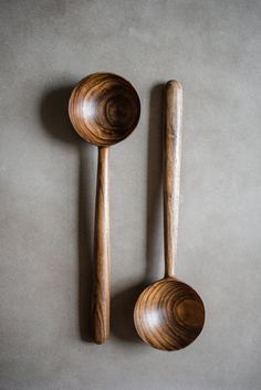 two wooden spoons sitting next to each other on top of a gray tablecloth