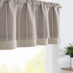 a close up of a window with a curtain in front of it and a potted plant next to the window