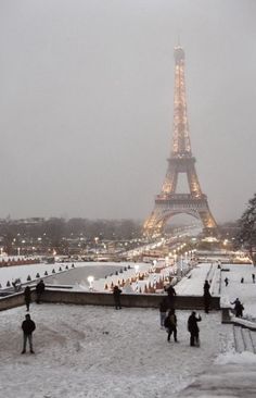 the eiffel tower is lit up in the snow