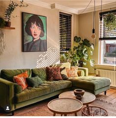 a living room filled with green couches next to a window covered in plants and potted plants