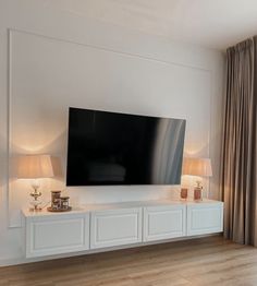 a flat screen tv mounted to the side of a white wall in a living room