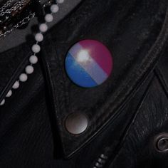 a black leather jacket with a blue and red button on it's lapel