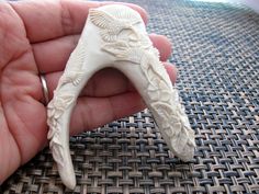 a hand holding a white carved animal head