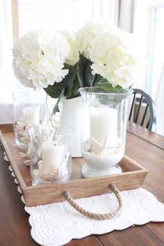 a wooden tray topped with white flowers and candles