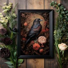 a black bird sitting on top of a wooden table next to flowers