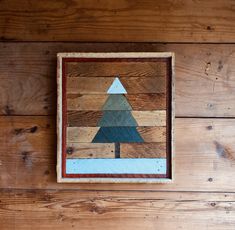 a wooden wall hanging with a small tree on it's side and wood planks in the background