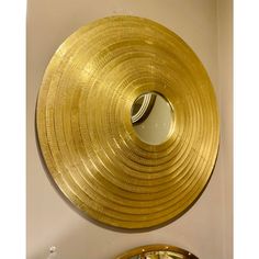 a round mirror hanging on the wall next to a gold plate with a circular design