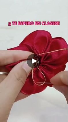 a person is tying a red ribbon around a flower that has been pinned to it