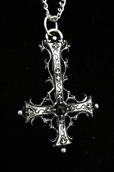 The Traumaturgist's Cross is a handcrafted piece made from fine pewter, containing 98% tin, featuring an intricate gothic inverted cross design that measures 7 cm in height. This pendant is adorned with a gemstone of your choice, allowing for personalization and enhancement of its significance. It comes with a choice of a stainless steel chain in either 18 or 24 inches, ensuring durability and hypoallergenic properties. The inverted cross is a powerful symbol often associated with the themes of Gothic Silver Necklaces With Antique Finish, Silver Gothic Necklaces With Antique Finish, Silver Gothic Necklace With Antique Finish, Gothic Cross Necklace With Oxidized Finish, Gothic Oxidized Cross Necklace, Gothic Pendant Necklace With Antique Finish, Gothic Metal Jewelry With Antique Finish, Antique Nickel-free Cross Pendant Jewelry, Gothic Cross Pendant Necklace With Engraving