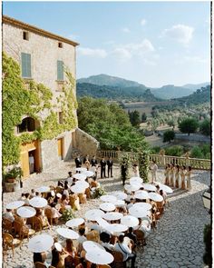 an outdoor ceremony with umbrellas set up in front of a stone building and trees