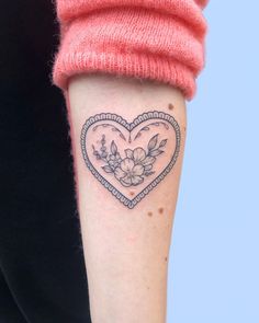 a woman with a heart shaped tattoo on her arm