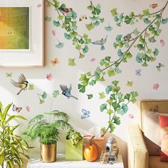 a living room filled with lots of plants and wallpaper covered in birds on it