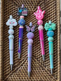 four pens are lined up on a wicker basket with some animal magnets attached to them