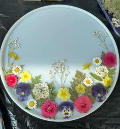 a plate with flowers on it sitting on top of a black table cloth next to other items