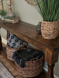 a wooden table topped with a basket next to a plant