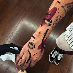 a person with a tattoo on their arm holding onto another persons hand while they both wear black and white shoes