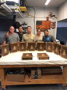 five men standing behind a table with wooden boxes on it and an american flag in the background