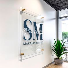 there is a sign that says make up artist on the wall next to a potted plant