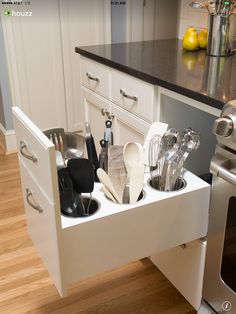 an open drawer in the middle of a kitchen with utensils and spoons