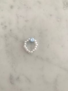 a pearl and white beaded ring on a marble surface