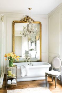 a bathroom with a tub, chandelier and mirror on the wall above it