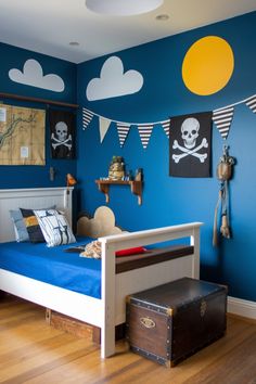 a child's bedroom decorated in blue and white with pirate flags on the wall