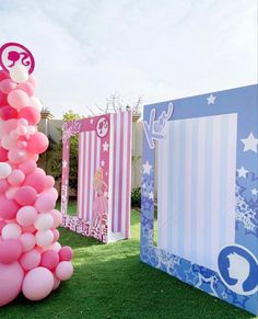 pink and white balloons are on display in the grass