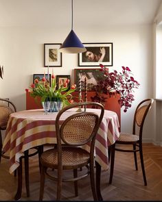 a dining room table with flowers in a vase on the top and chairs around it