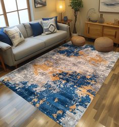 a living room filled with furniture and a blue rug on top of a hard wood floor