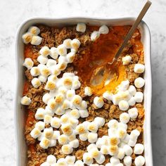 a casserole dish with marshmallows and orange sauce