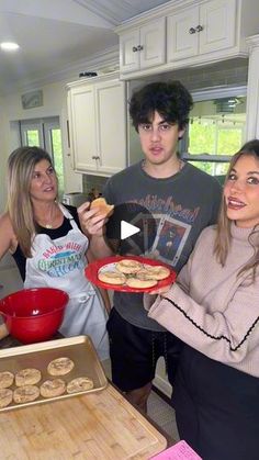 a group of people standing around a table with food in front of them and one person holding a plate