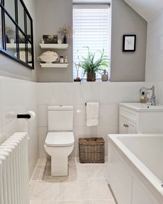 a white toilet sitting next to a bath tub in a bathroom under a window with shutters