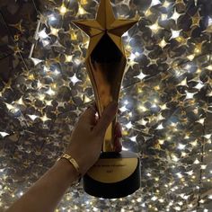 a person holding up a trophy in front of a star ceiling