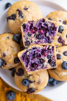 blueberry muffins stacked on top of each other in a white plate with one cut in half