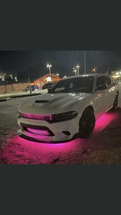 a white car with pink lights on it's hood parked in a parking lot