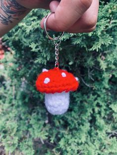 a hand holding a red and white mushroom keychain