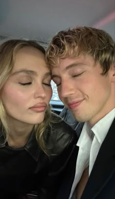 a young man and woman are kissing in the back seat of a car, with their eyes closed