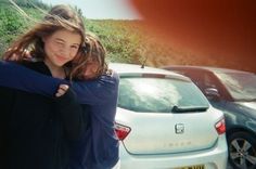 two girls hugging each other in front of parked cars