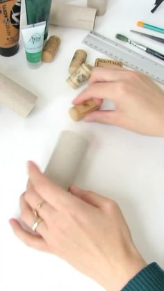 two hands are holding corks on a table with other crafting supplies and tools