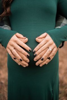 a pregnant woman with her hands on her belly, wearing a green long sleeved dress