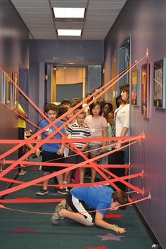 a group of children standing in a hallway with red tape on the floor and walls